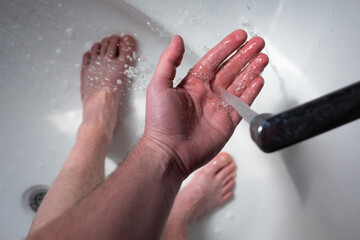 Cold water flows from the faucet. a man is trying to take a cold shower.