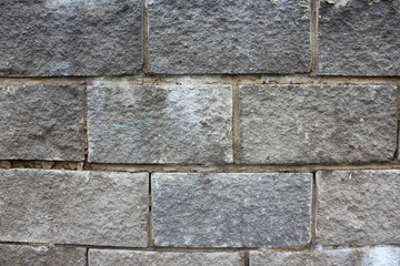 An old gray brick wall with raw seams, close-up. Background texture.