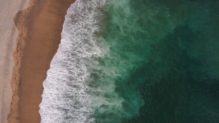 Aerial view on the beach with aquamarine sea and waves breaking on the beach