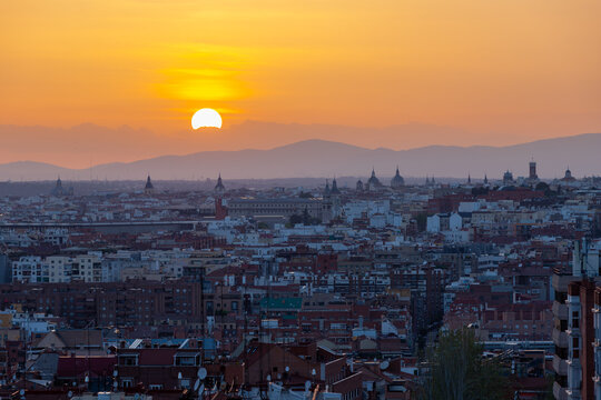 An amazing warm sunset over the skyline of Madrid with views on the mountain range, 
Sierra de Guadarrama on the horizon, seen from las siete tetas on Cerro Tio Pio hill side.