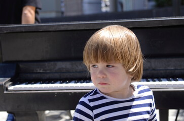 Portrait of a little boy. The child is crying near the piano. Music lessons for the little ones.
