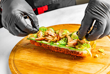 Chef's hands in gloves cooking sushidog with tuna and vegetables on kitchen