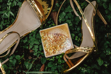Box with sequins on a background of golden sandals in a tropical environment
