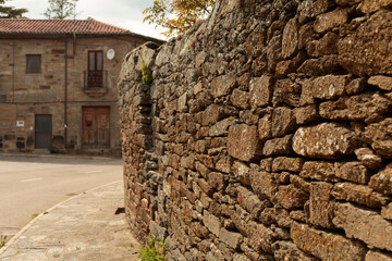 a stone old wall in a  little village street 