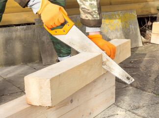 The process of manual sawing timber. a man sawing a timber when building a house