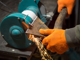 man sharpening an ax blade on a grinder