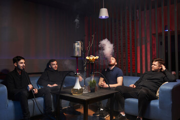 young men sit in a hookah room and smoke a hookah. atmospheric cafe with hookah