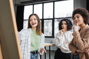 Cheerful multiethnic businesswomen looking at blurred board in office.