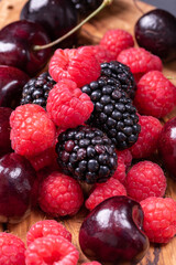 strawberries, blackberries and cherries on wooden chopping board