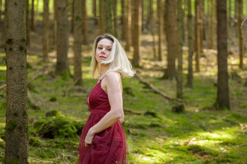 Obraz na płótnie Canvas Blond woman turning around against trees in woods.