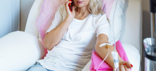 Woman in a hospital talking on a mobile phone with a drip in her arm.