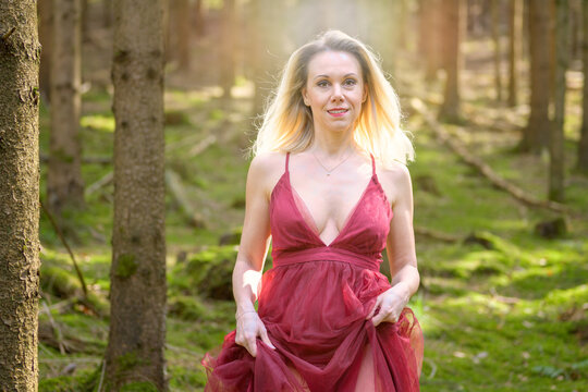 Sensuous blond woman in magenta dress at woods.