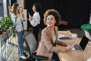 Positive african american businesswoman looking away while using devices in office.