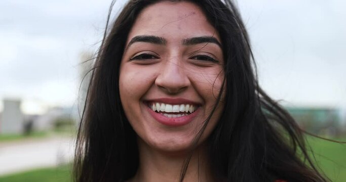 Young indian woman smiling on camera at city park 