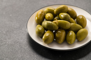 Large green pickled olives on a dark gray background, close-up