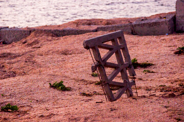 Fototapeta premium a damaged piece of concrete fence sticks out of the sand on the wild sea beach