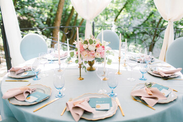 Wedding decor in blue. Banquet tables decorated bouquet with peonies on the tables are pink plates, glasses and candles
