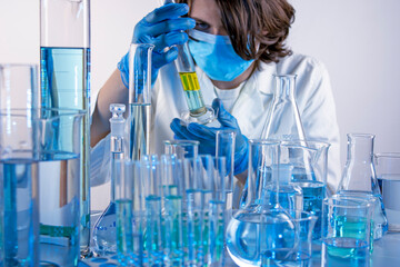 Young scientist mixing liquids with beakers and flask, in a laboratory
