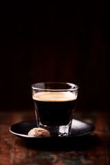 Coffee in glass cup on dark wooden background. Copy space.