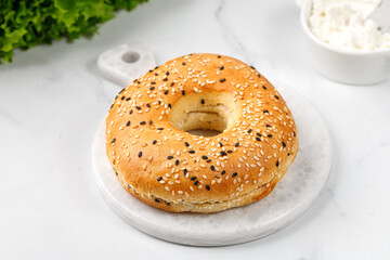 Empty sesame bagels on marble board. Freshly baked bagel.