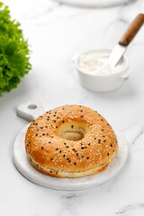 Bagel with sesame seeds on marble board on white background. Empty bagel