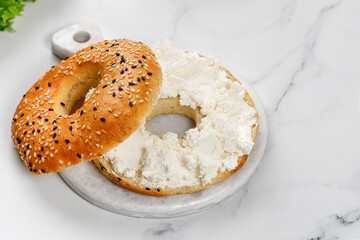 Freshly baked bagel sandwich with cream cheese on marble background