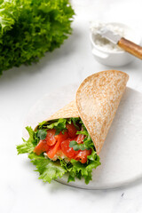 Wrap sandwich, roll with salmon and lettuce leaves. Tortilla wraps with salmon and micro greens.