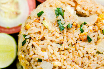 Fried rice and vegetable in black dish on tablecloth. Thai food style.