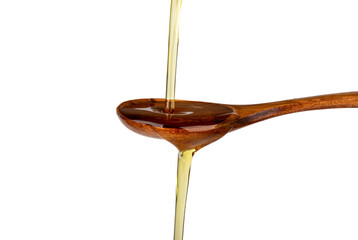 Jet of sunflower oil pours from above onto a wooden spoon and flows down on a white background.