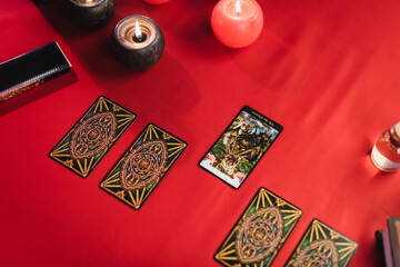 KYIV, UKRAINE - FEBRUARY 23, 2022: Top view of tarot cards near burning candles on table.