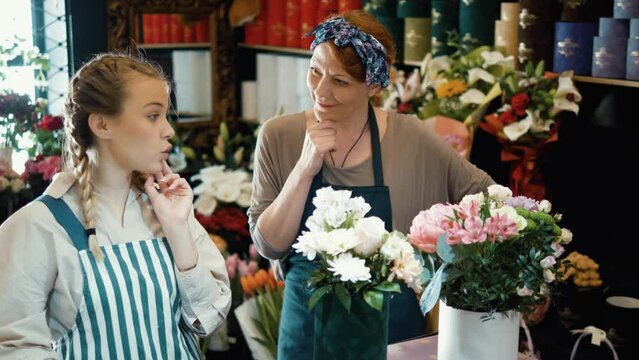 Busy female florist workers working  in flower shop. Mature woman and a young girl are thinking about ordering at a flower shop