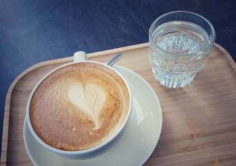 Cup of coffee and glass of water on wooden tray - 503122748