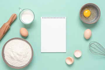 Baking ingredients and a blank notepad. Mint pastel color background. Top view, flat lay, place for recipe.