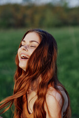 Naklejka premium A beautiful redheaded woman laughs and smiles with her teeth in the bright sunset sunlight. The concept of healthy living and good nutrition