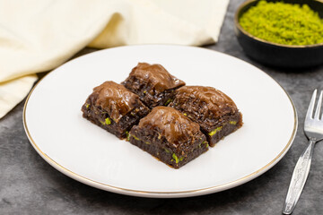 Chocolate baklava. Chocolate baklava with pistachio on dark background. Mediterranean cuisine delicacies. Close-up. local name cikolatali baklava