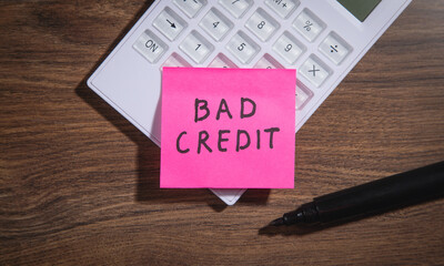 Bad Credit on sticky note with marker, calculator.