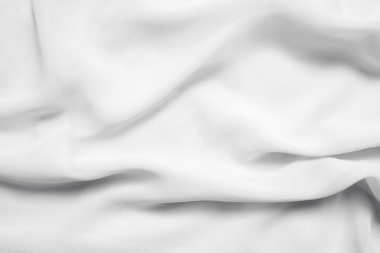 White wavy folded fabric, cloth as texture or background, top view for overlay
