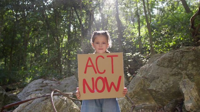 The girl raises a poster with the inscription act now. A single protest against the ecological situation and environmental pollution. The concept of World Environment Day.