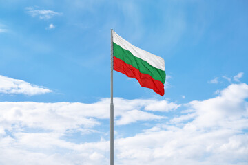 Flag of Bulgaria is waving in front of blue sky and clouds