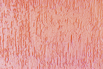 The pink plaster texture of the exterior wall of the building is close-up. Deep touches in the plaster.