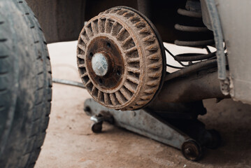 Car repair, close-up replacement of rusty rear wheel drum brake, outdoors