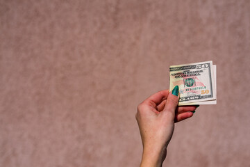 Hand holding showing a 50 dollar banknote, giving or receiving money like tips or salary.