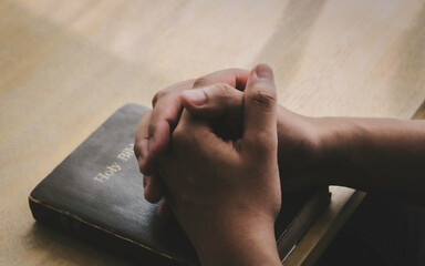 Human hands praying for God's blessings on a wooden table for a better life.  Christian Crisis...