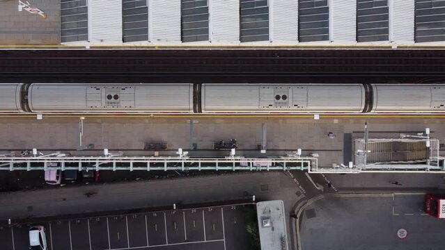 A drone view of a short tube train leaving Putney Bridge station in London.