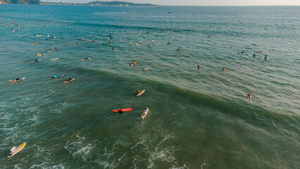 Surfers with boards in the water waiting for the waves in the ocean, top shot, drone photo.