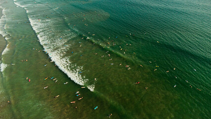 Surfers with boards in the water waiting for the waves in the ocean, top shot, drone photo.