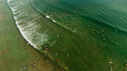 Surfers with boards in the water waiting for the waves in the ocean, top shot, drone photo.