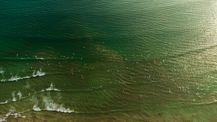 Surferzy w oceanie z deskami, widok z drona.