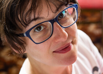 Close-up of young woman's face in blue glasses and with no makeup. Natural image without retouching