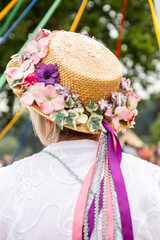 Vertical shot of a traditional English Maypole dancer with a floral hat with colorful ribbons